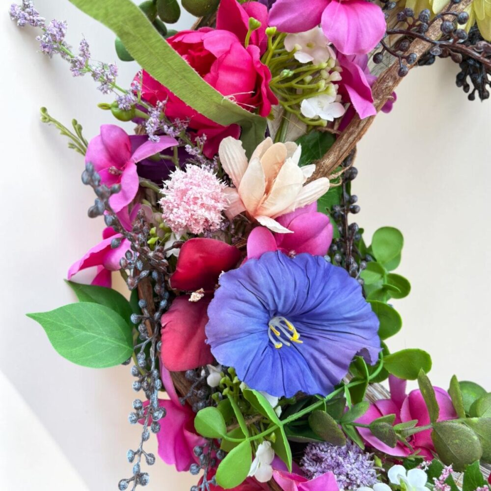 Kleurrijke zijden bloemenkrans Berry Gloss met roze, rode, blauwe en gele bloemen op natuurlijke takkenbasis.
